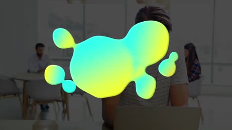 Animation-of-glowing-blob-over-businessman-using-laptop-in-office