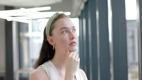 thinking deeply, woman with hand on chin in modern office setting