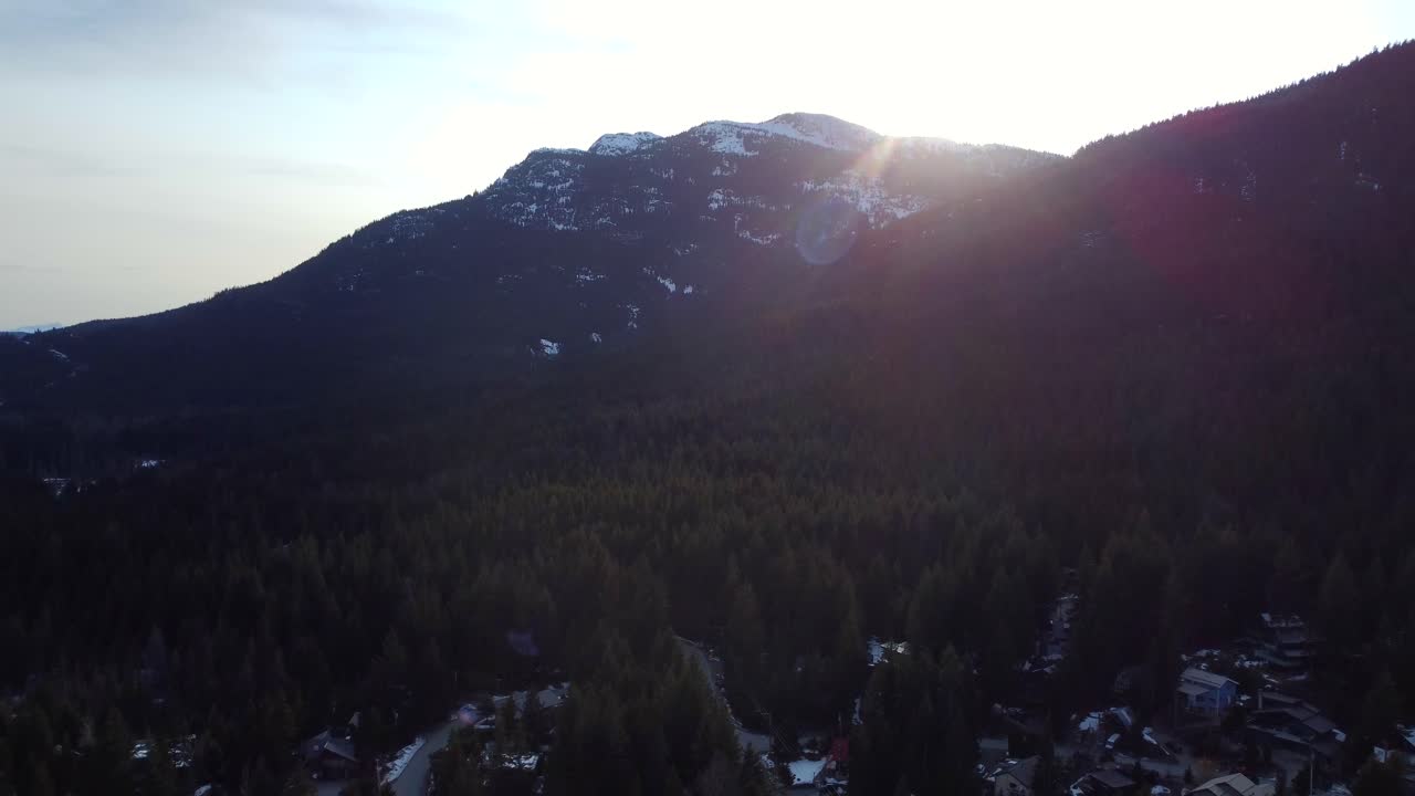 Drone shot cinematic lens flare at sunset with mountains and forest in Canada
