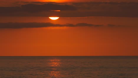 Orange-ocean-sunrise-over-calm-sea-reflecting-sunlight-on-water