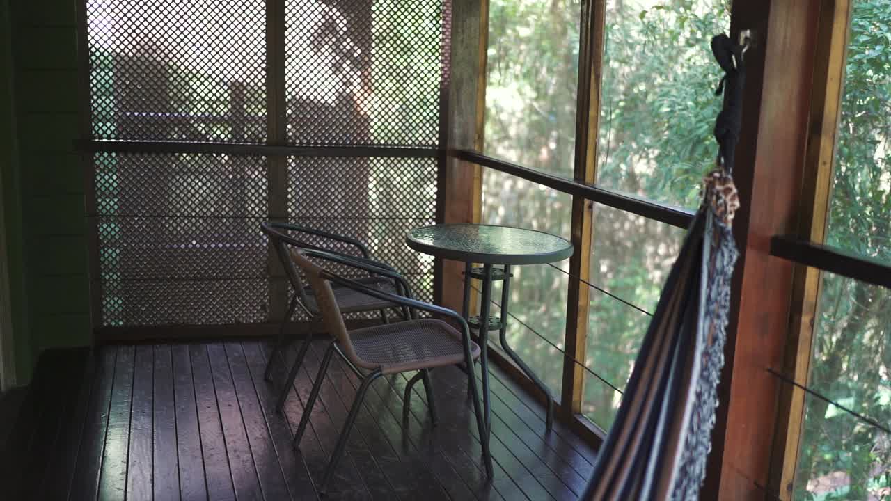 Wooden deck with table and two chairs in a room in a rural vacation rental house. Argentina.