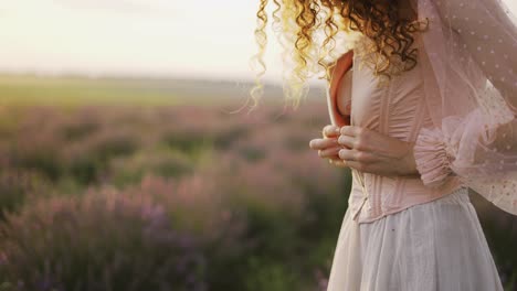 Chica-De-Pelo-Rizado-Con-Un-Vestido-Rosa,-Apretando-Su-Corsé-Entre-Un-Campo-De-Lavanda-Púrpura