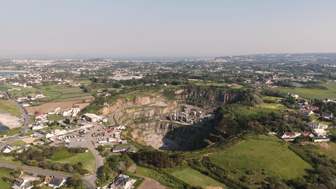 High Rising Drone footage approaching Les Vardes Quarry Guernsey showing quarry, equipment and surrounding area on bright sunny day
