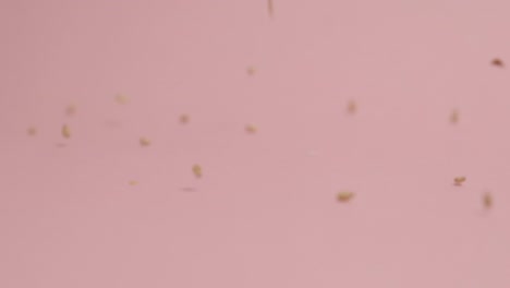 sesame seeds falling on pink background