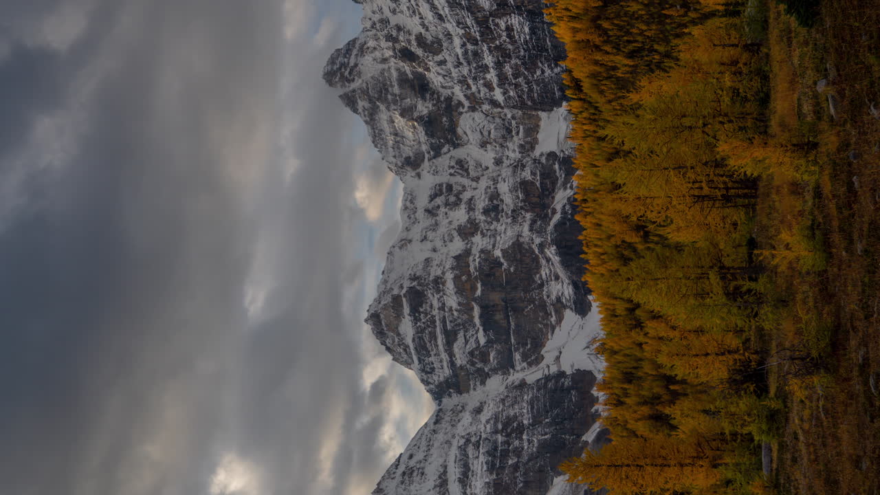 4k vertikal timelapse, dramatiske mørke skyer bevæger sig over snedækkede toppe og larch dal på en kold efterårsdag i banff national park, canada