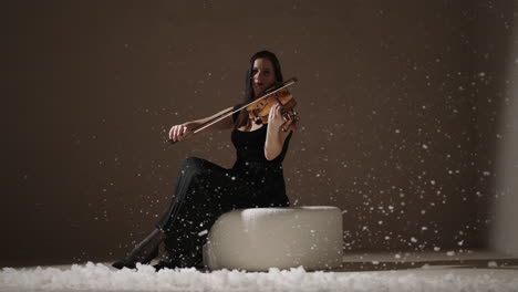 woman playing violin in winter studio setting