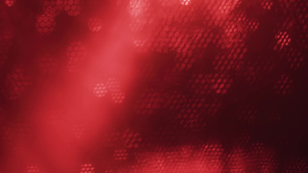 Red abstract optical blurred background. Optical bokeh overlapped by moving honeycombs.