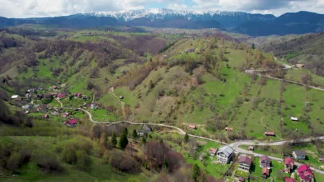 fotografía aérea sobre los frondosos bosques verdes de rumania, revelando gradualmente la majestuosa cordillera de piatra craiului en la distancia