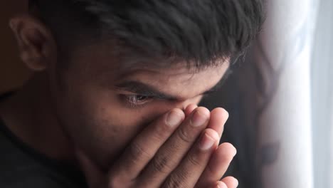 un joven triste cubriendo su cara.