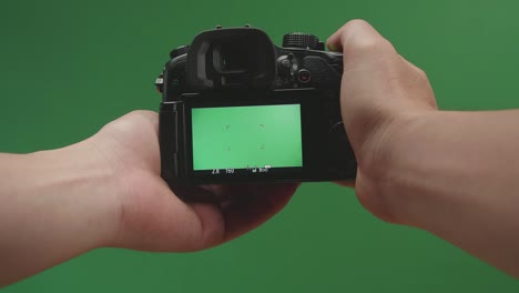 male hands taking photos with green screen display camera in green background