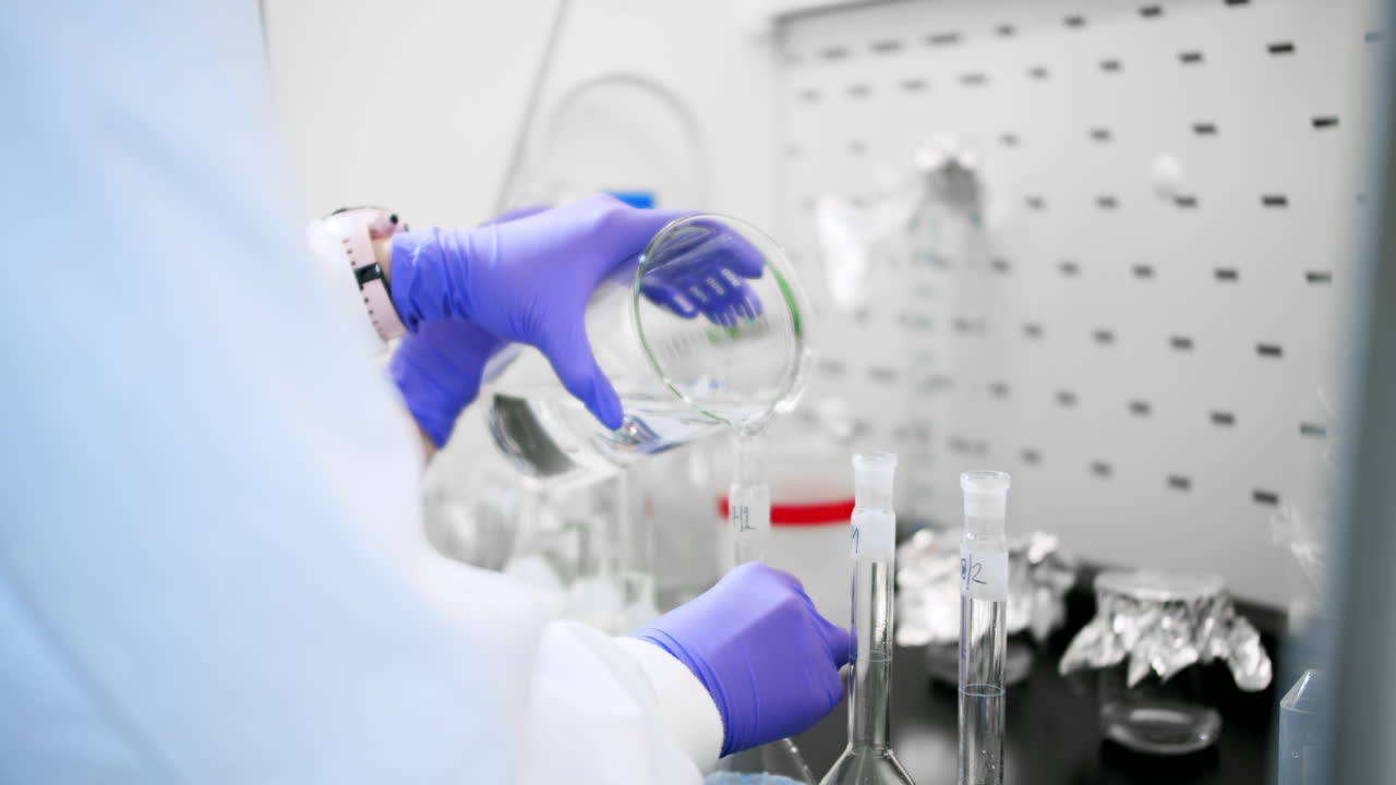 A scientist in lab is pouring the liquid in containers in the search for a cure