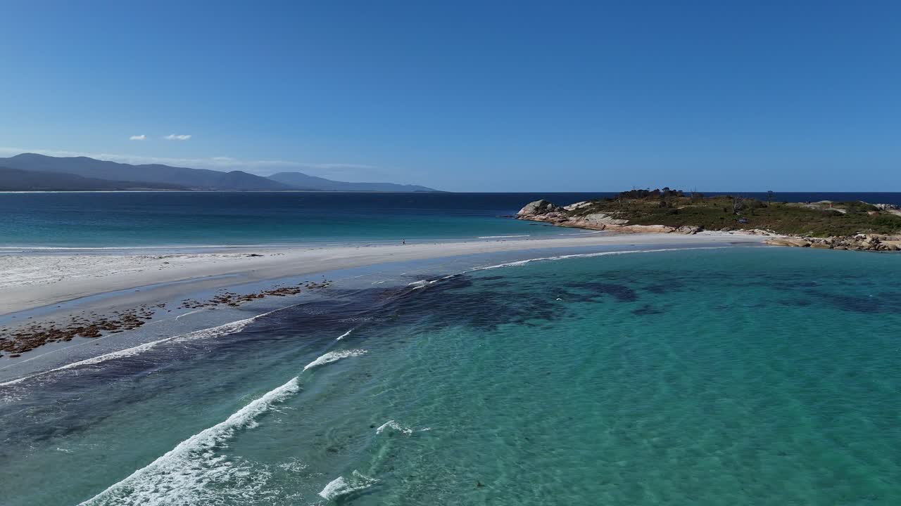 las olas de turquesa del océano índico llegan a la playa de arena de tasmania.