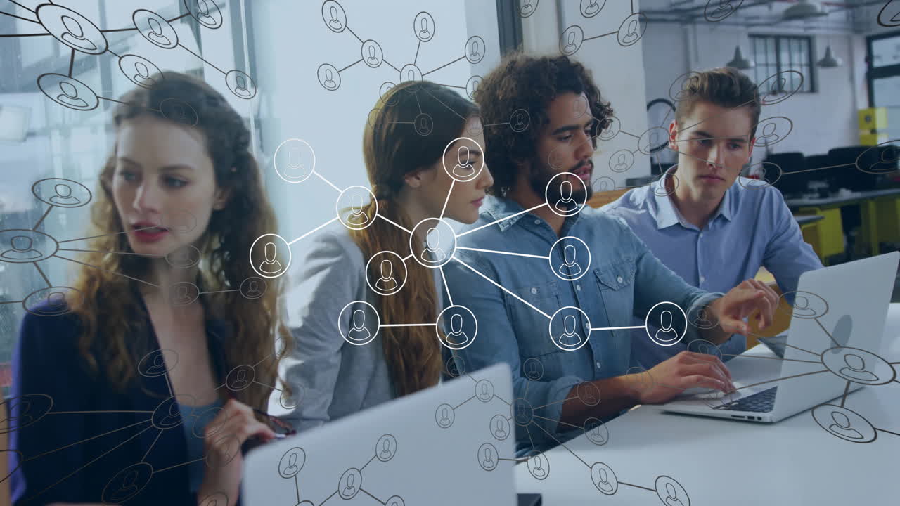 Tech team collaborating around laptops on conference table, showcasing animated network diagrams