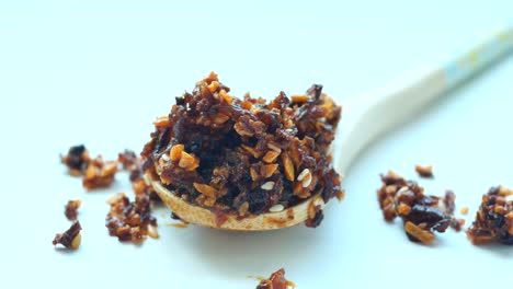 chili and garlic flakes on wooden spoon on white background