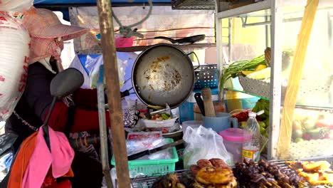 street food. a woman shifts food from a cauldron to a disposable food container