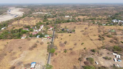 Linear-black-asphalt-road-with-big-villas-in-the-dry-environment-of-Yopal-with-in-the-background-the-dry-river-Rio-Cravo-Sur