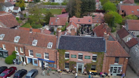 toma aérea de un dron deslizable lateralmente de la hermosa y antigua aldea de tiendas y casas del mercado de burnham en un día soleado y nublado en el norte de norfolk, reino unido