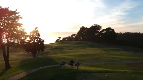 ein schöner abend, an dem drei freunde den sonnenuntergang genießen, während sie bei diesem golfspiel zum nächsten loch gehen