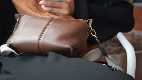 woman sitting with brown leather shoulder bag