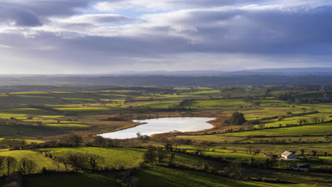 Lapso-De-Tiempo-Del-Paisaje-Agrícola-Rural-Con-Lago-En-Campos-De-Hierba-Y-Colinas-Durante-Un-Día-Nublado-Visto-Desde-Las-Cuevas-De-Keash-En-El-Condado-De-Sligo-En-Irlanda