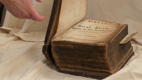 male hand shuts the cover of very old thick historical bible