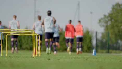 Tiro-Estático-En-Cámara-Lenta-De-Jugadores-De-Fútbol-Fuera-De-Foco-Trotando