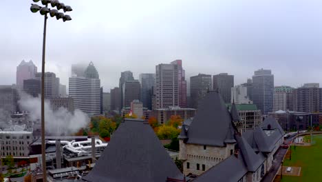 Drohnenschuss,-Der-An-Einem-Nebligen-Herbstmorgen-An-Einem-Alten-Gebäude-Vorbeifährt-Und-Die-Skyline-Der-Innenstadt-Von-Montreal-Enthüllt