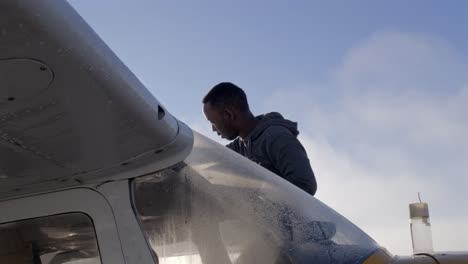 male black pilot checks fuel level in the wing of an airplane slomo