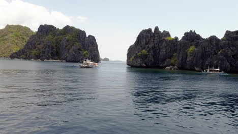 Cinematic-aerial-drone-flight-showing-the-Palawan-Cliffs-with-Boats-and-mountains-in-view-in-the-Philippines,-Asia