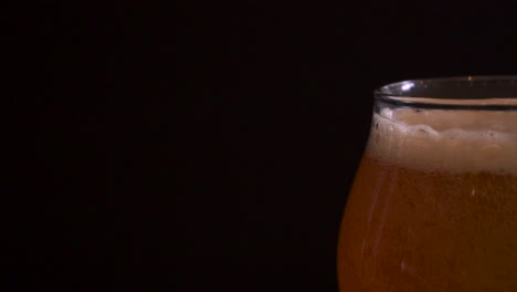 Fancy-pint-of-craft-beer-sitting-on-a-table-with-black-background,-slow-motion-truck-right