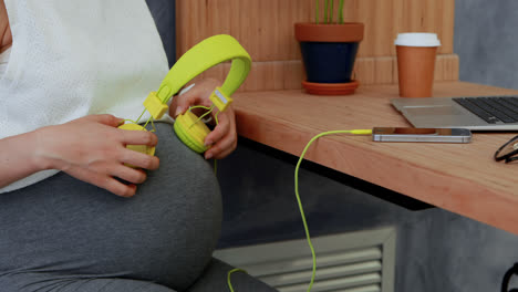 pregnant woman placing headphones on her belly 4k