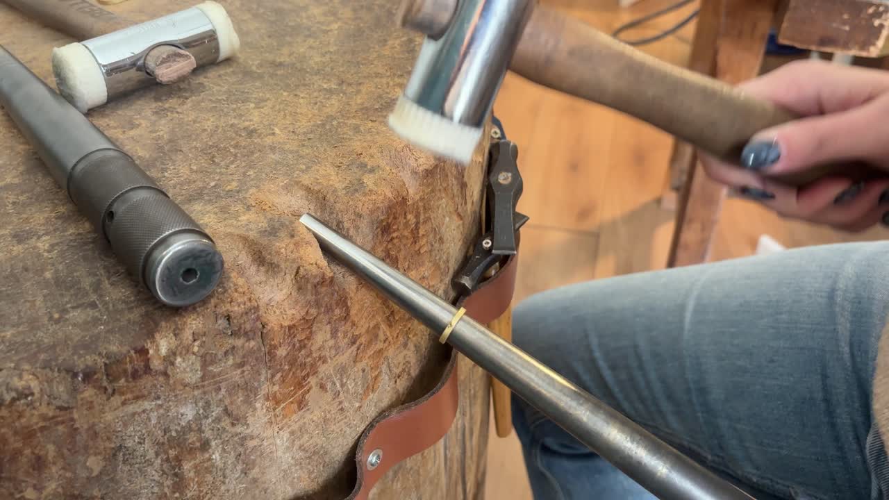 Woman forging a wedding ring with a hammer in a workshop