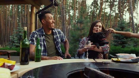 Positive-man-and-woman-laughing-outside.-Relaxed-girl-playing-with-dog-on-picnic