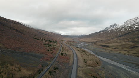 subida aérea mirando hacia abajo en los coches que conducen la autopista del valle a través de la cordillera de islandia