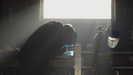 silhouette of worker welding metal parts in workshop