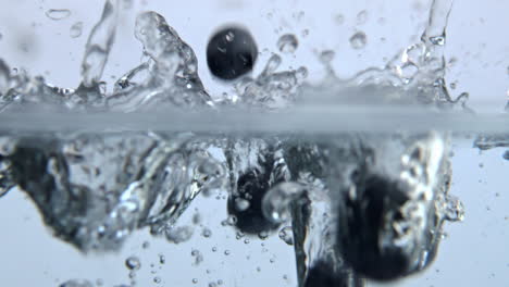 bayas cayendo por el agua con blebs de cerca. arándanos maduros burbujeando líquido