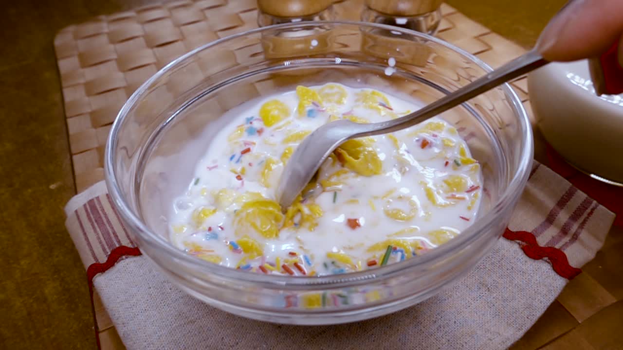 flocos de maíz amarillos crujientes en el cuenco para la mañana un delicioso desayuno con leche. cámara lenta con toma de seguimiento de rotación.