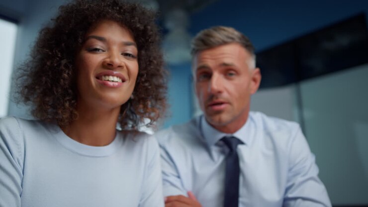 Joyful businessman and businesswoman making video conference online with clients