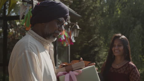 an indian man in a turban receives a gift at an outdoor celebration