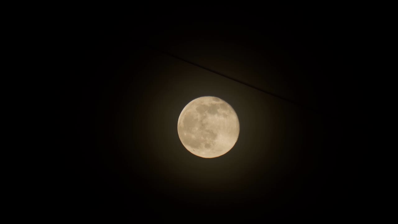 A lua cheia amarela contra o fundo do céu noturno escuro, um fio pendurado de edifícios