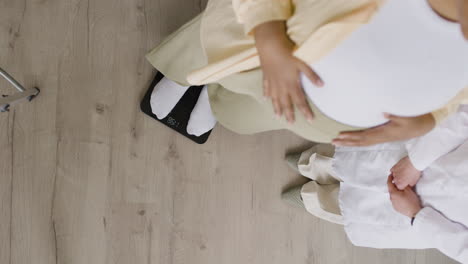 pregnant woman weighing herself at doctor's office