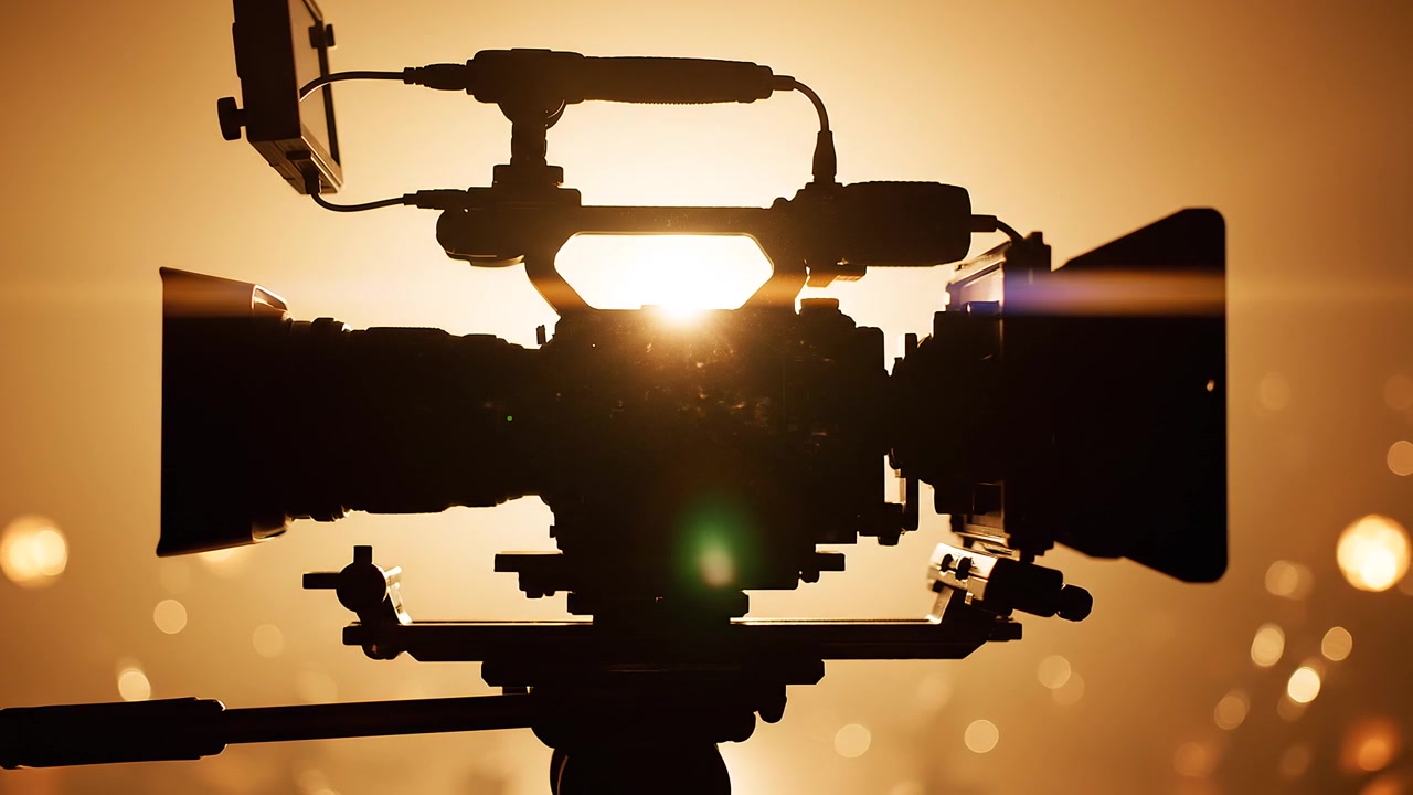 Professional cinema camera silhouette with warm backlit sunset lighting
