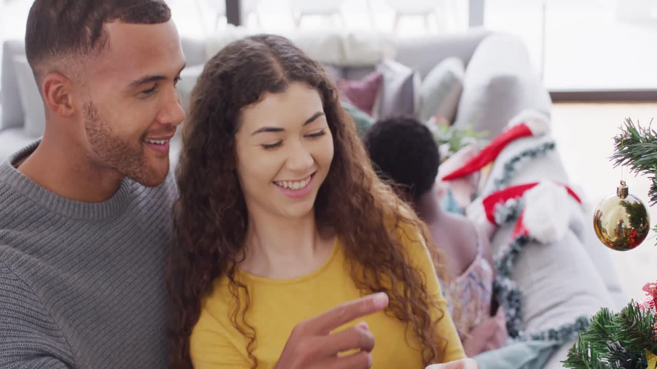 un grupo feliz de amigos diversos decorando el árbol de navidad