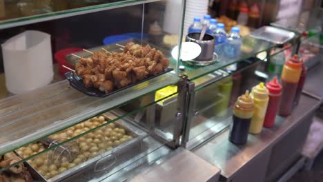 shelf with meat skewers at delicatessen shop with bottles of sauce condiments in mong kok