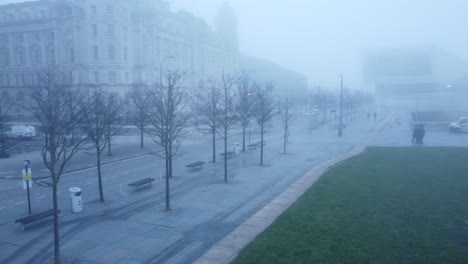 thick dense ghostly morning fog cover across liverpool city aerial view of surreal downtown waterfront pan left rising shot