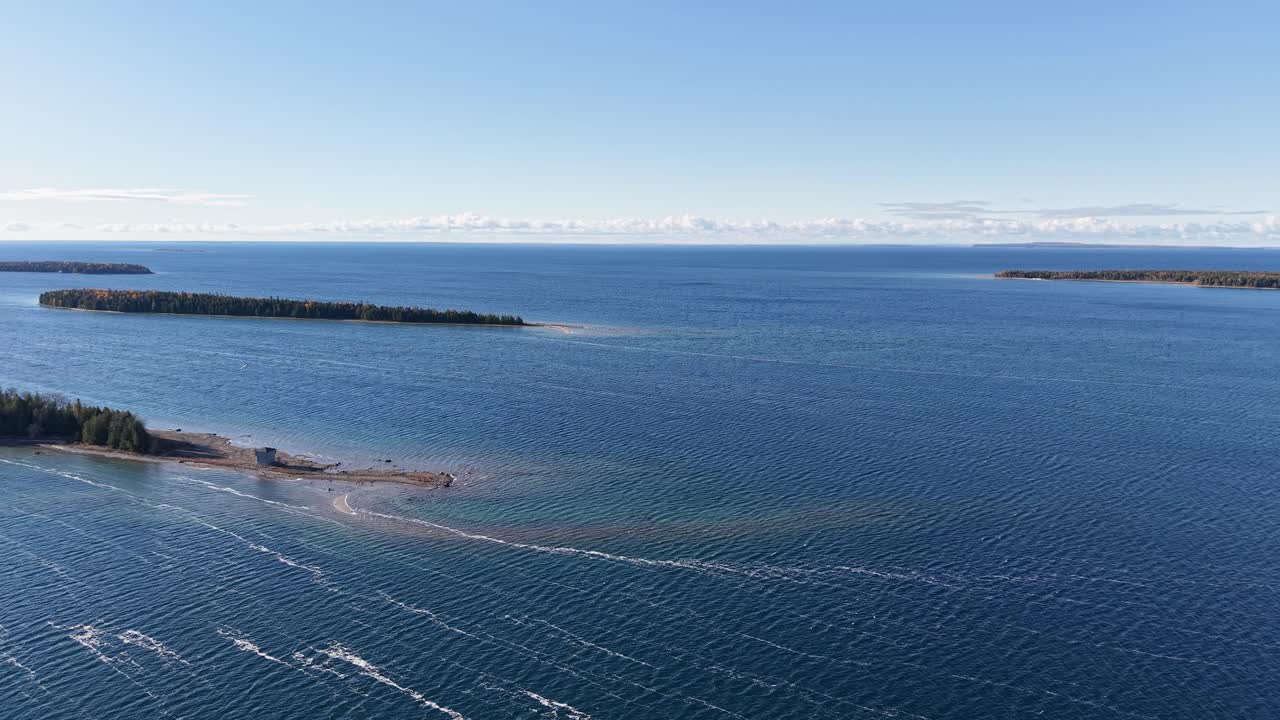 Aerial view of deep blue lake with islands and sandbars stretching toward the horizon on a clear day