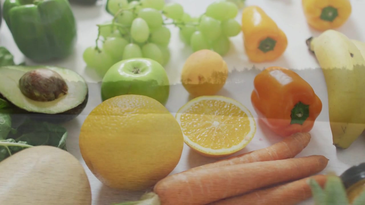 Video verticale: Telecamera in panoramica che rivela un avocado e un'arancia tagliati a metà su un tavolo bianco, mostrando la composizione.