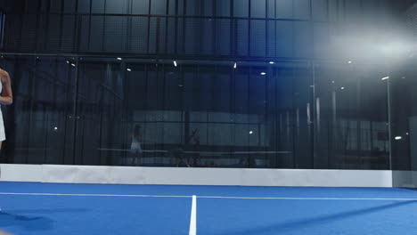players engaged in intense padel tennis match on blue indoor court, focusing on game