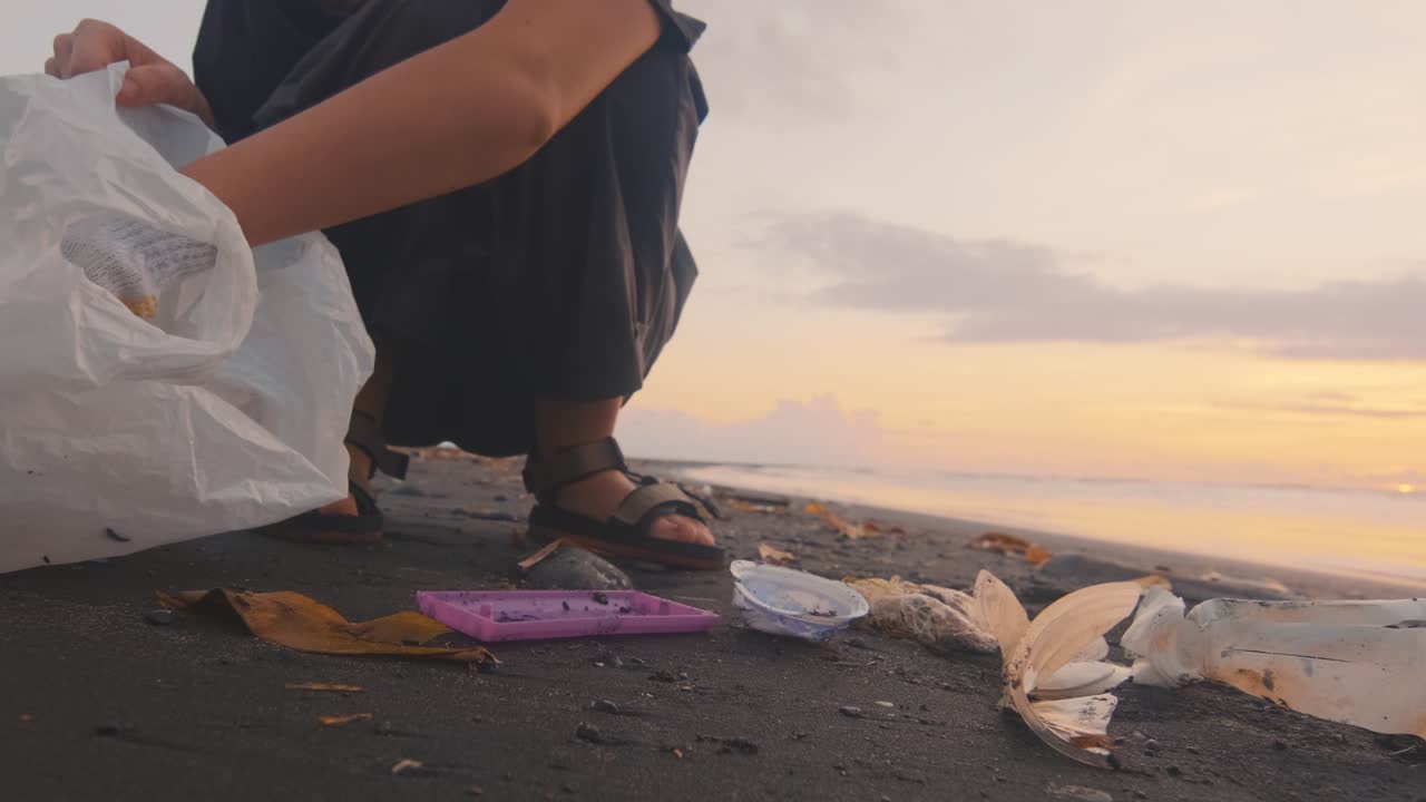 Volontaria pulisce la spiaggia dell'oceano dai rifiuti di plastica per il loro successivo smaltimento.