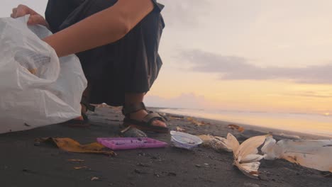 una voluntaria limpia la playa del océano de residuos plásticos para su posterior eliminación